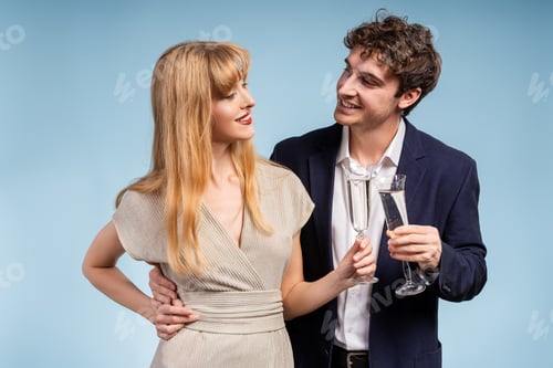 Preview: Elegant couple smiling and holding champagne glasses celebrating on blue background