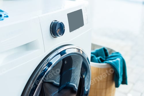 Preview: close-up view of modern washing machine and basket with laundry at home