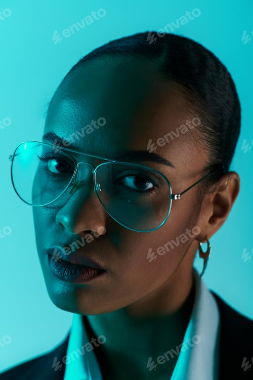 Preview: A young African American woman with glasses poses confidently in studio setting