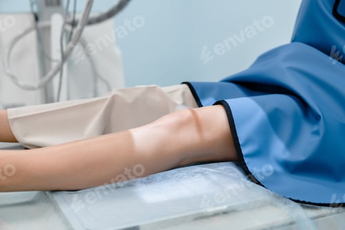 Preview: Cropped shot of patient in a protective suit lying on bed in X-ray machine for scanning leg knee