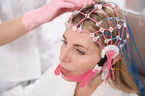 Preview: Doctor attaches cap with electrodes womans head for diagnostic procedure