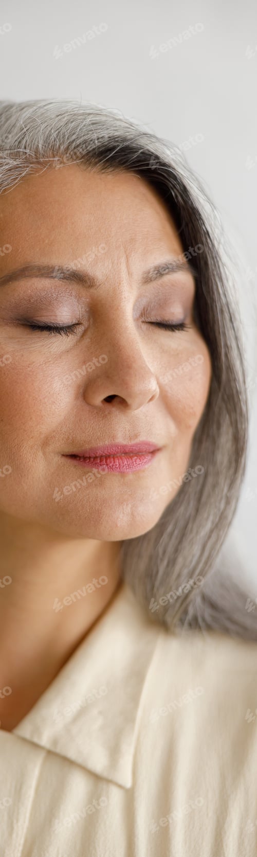 Preview: Calm middle aged woman with closed eyes stands on light background