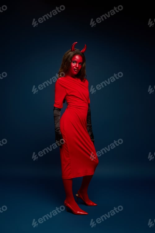 Preview: A stunning woman in a striking red Halloween costume with devil horns poses against a dark backdrop