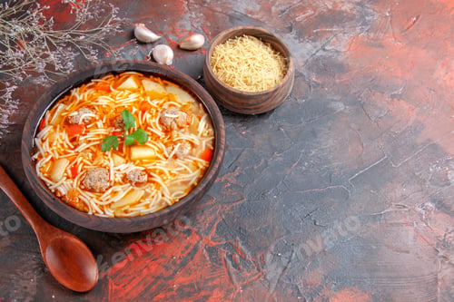 Preview: Delicious noodle soup with chicken and uncooked pasta in a small brown bowl and spoon on the dark