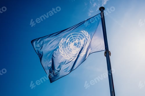 Preview: UN flag waved against the sun and blue sky.