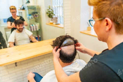 Preview: Hairdresser attaching a capillary prosthesis using adhesive stickers