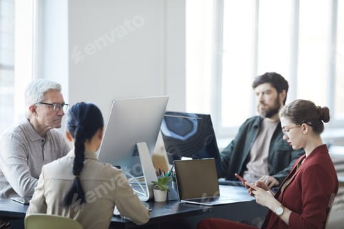Preview: Business Professionals Collaborate at Desks in Bright Office