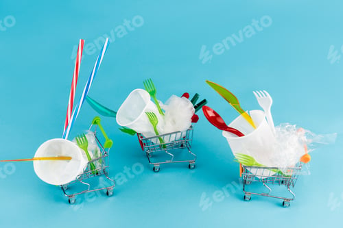 Preview: disposable plastic objects in small shopping carts on blue background