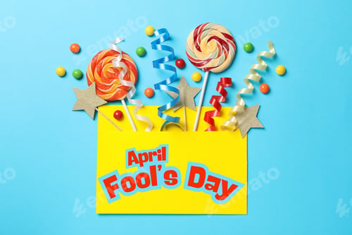Preview: April Fool's Day, candy canes and confetti in an envelope on a blue background, top view