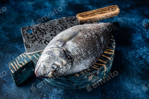 Preview: Sea bream or dorado fish on fish market cutting board. Blue background. Top view