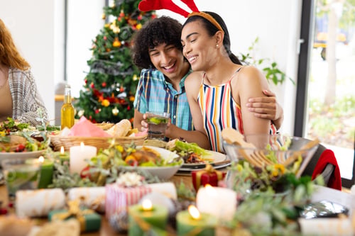 Preview: Happy diverse friends sitting at table and having dinner at christmas