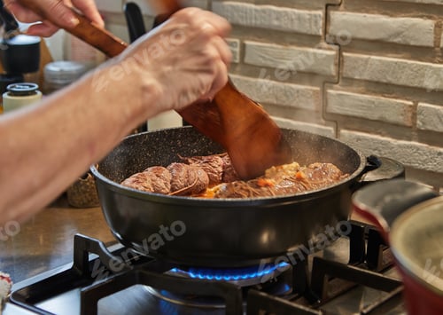 Preview: Chef fries meat rolls in a frying pan on a gas stove. French gourmet cuisine