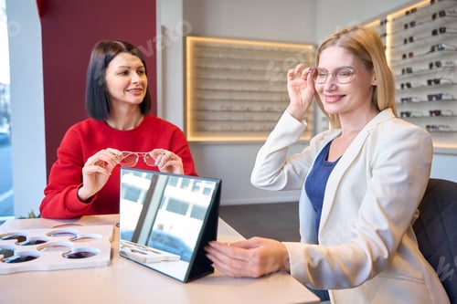 Preview: Smiling woman trying on glasses with stylish frames