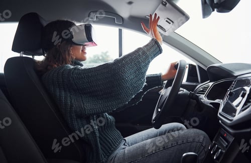 Preview: Side view of woman in virtual reality glasses that sitting inside of modern car