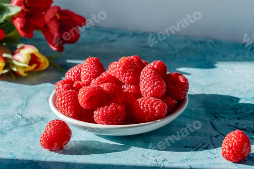 Preview: Fresh Raspberries In White Bowl On Blue Table