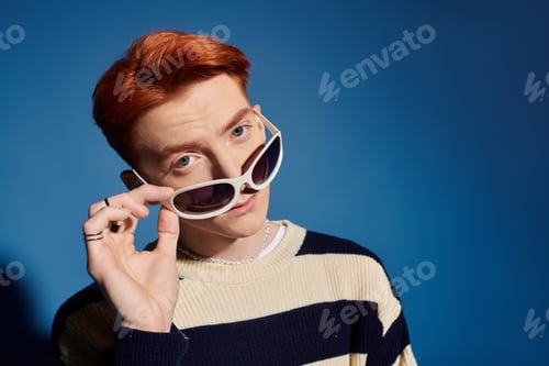 Preview: Emotional young man with striking features expressing creativity against a vibrant blue backdrop