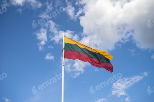 Preview: Low angle view of the flag of Lithuania on a metallic pipe under a blue sky and sunlight