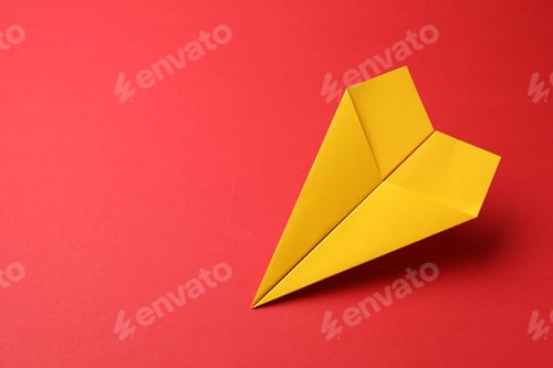 Preview: Handmade yellow paper plane on red background, space for text