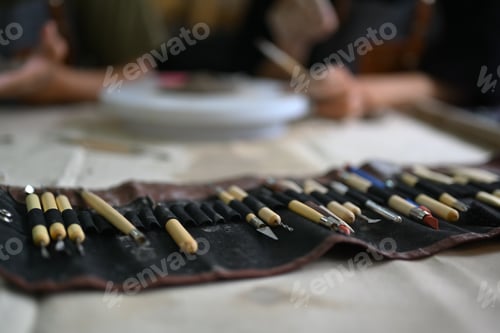 Preview: Closeup shot of various tools for pottery on table in workshop.