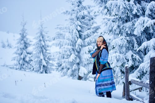 Preview: Young woman in blue dress, embroidered warm sleeveless fur coat and kerchief with floral design.