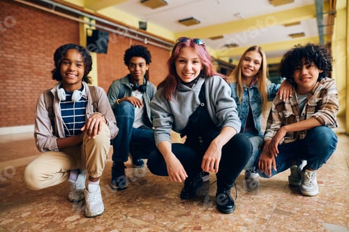 Preview: Group of happy high school friends in hallway looking at camera.
