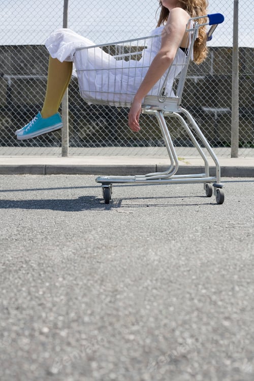 Preview: Young person sitting in a shopping cart on a sunny day