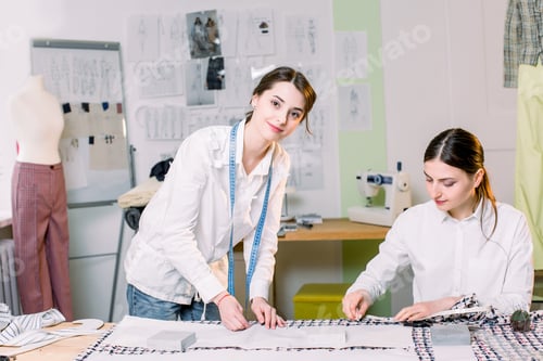 Preview: Two pretty women dressmakers working in the fashion atelier with stylish fabric on which they have