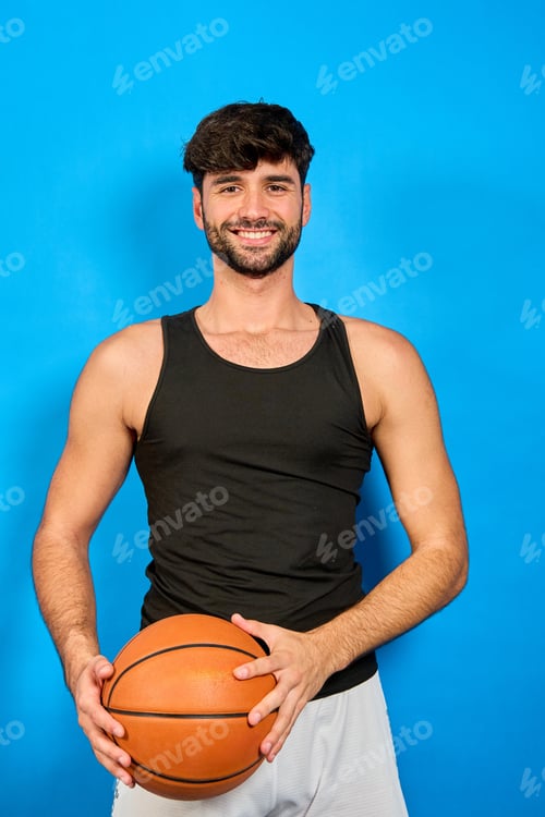 Preview: Smiling basketball player holding ball on blue background