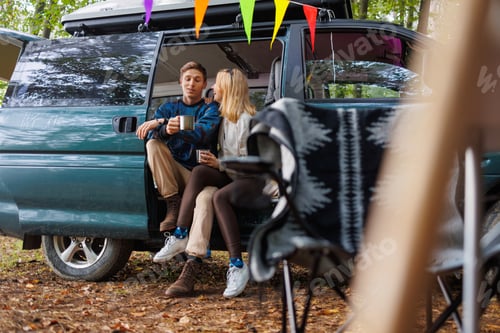 Preview: Young Couple Relaxing with Tea in Camp Setting