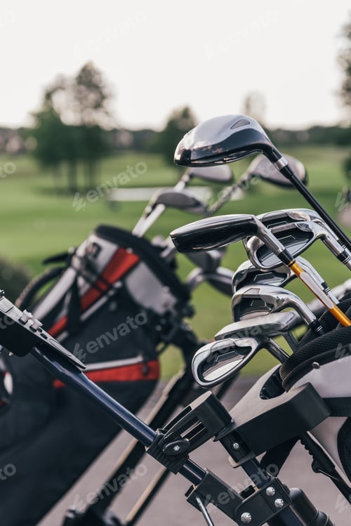 Preview: Close-up view of shiny golf clubs in golf bags outdoors