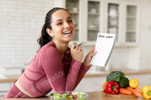 Preview: Happy Fit Young Lady Writing Diet Plan In Notebook Indoor