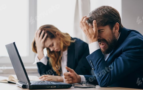 Preview: Business men and woman sit at a work table in front of laptop emotions office