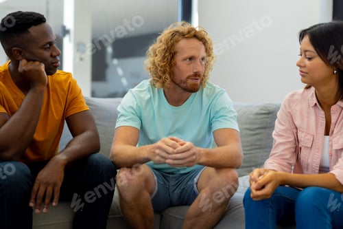 Preview: Group of diverse people sitting on sofa and talking in group therapy session