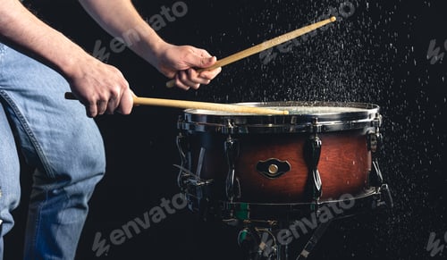 Preview: Drummer using drum sticks hitting snare drum with splashing water.