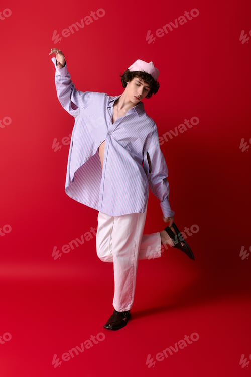 Preview: Stylish young man showcasing fashion flair against vibrant red backdrop
