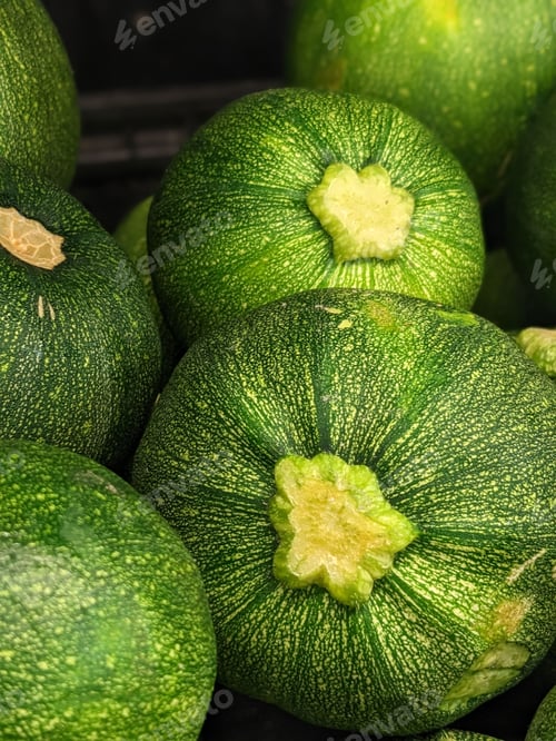 Preview: Closeup shot of a stack of fresh, green zucchini arranged in a neat pile on a white background