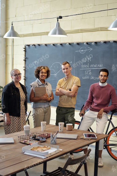 Preview: Happy young economists standing by table in large openspace office
