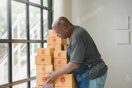 Preview: Man organizing stacked cardboard boxes by a window