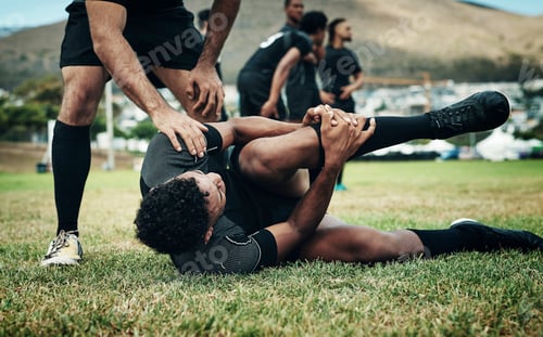 Preview: Cropped shot of a handsome young rugby player suffering with an injury on the field