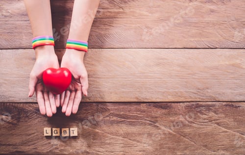 Preview: Hands with a rainbow color wristband Placed on a wooden floor . Gay rights fight.