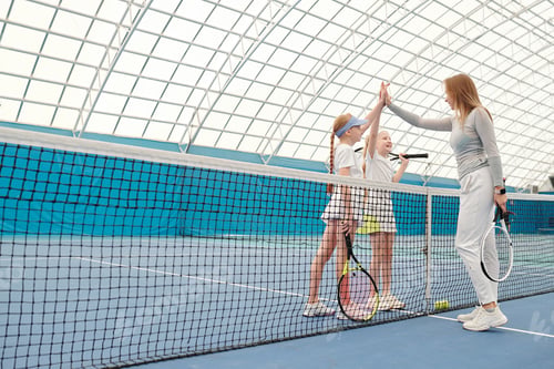 Preview: Happy preteenage girls in activewear giving high five to their tennis trainer