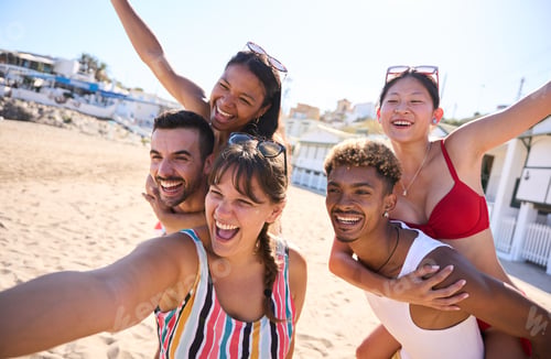 Preview: Group of cheerful diverse young gen z friends taking a selfie on the beach
