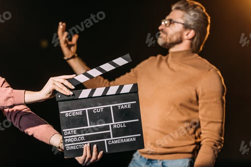 Preview: selective focus of mature actor performing role with clapboard in front