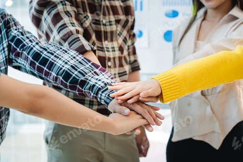 Preview: young business people putting their hands together. Stack of hands. Unity and teamwork concept.
