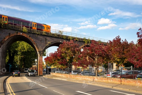 Preview: Train crossing viaduct over road with autumn trees.