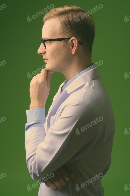 Preview: Young handsome man doctor with blond hair against green background