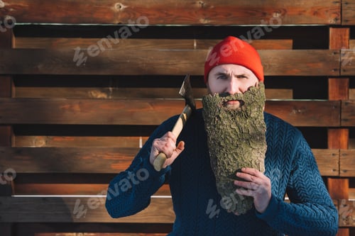 Preview: young man with beard made of wood bark and axe in hand outdoors