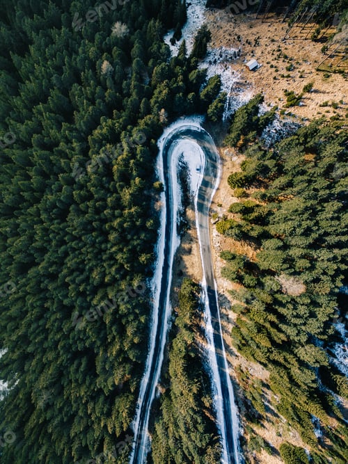 Preview: Aerial view of snowy forest with a road. Captured from above with a drone
