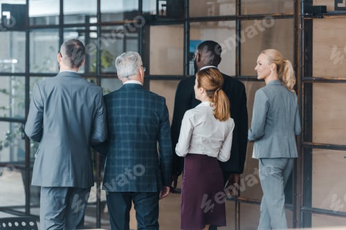 Preview: back view of multicultural businessmen and businesswomen walking in office