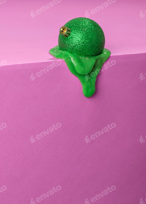 Preview: Green glittery Christmas ornament melting on a pink background.